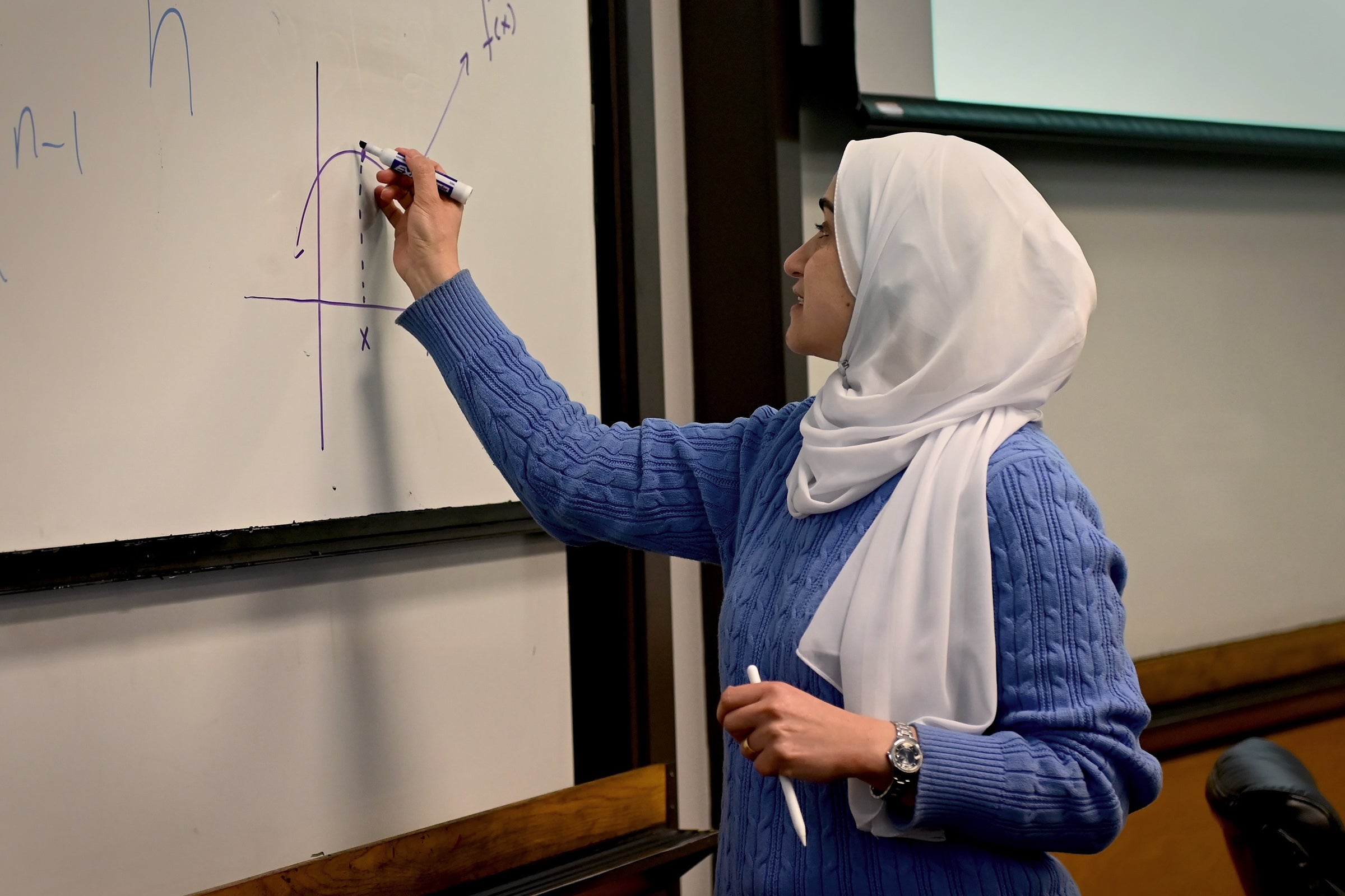 A photo of a mathematics professor writing equations on a board.