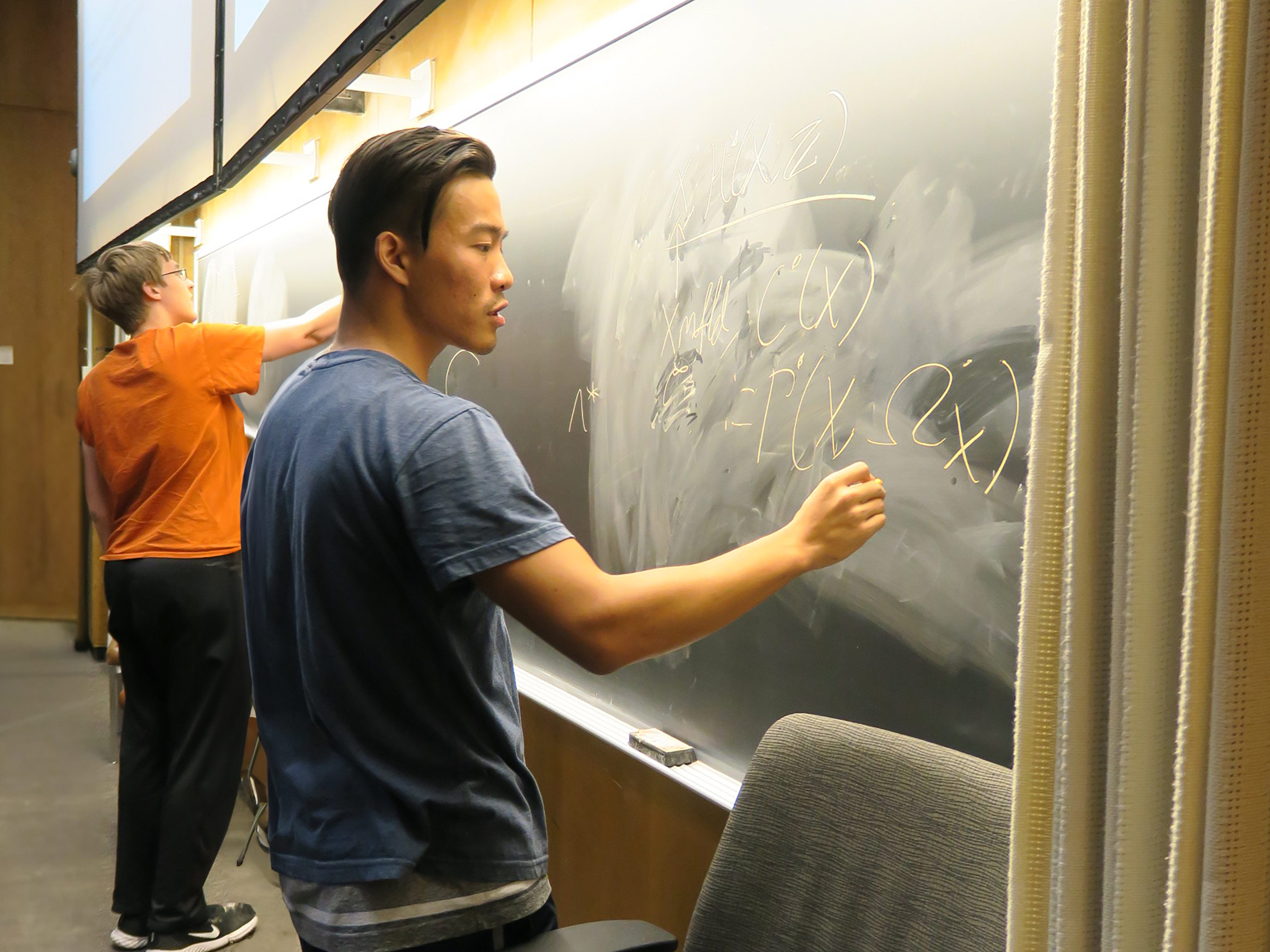 A photo of students writing equations on a chalkboard