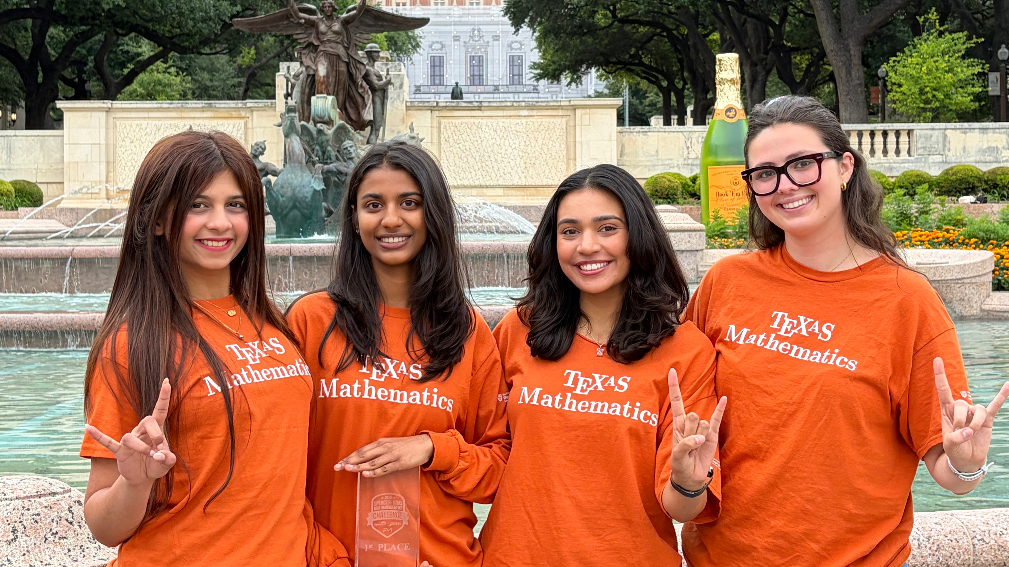Four UT students holding a trophy near the Tower