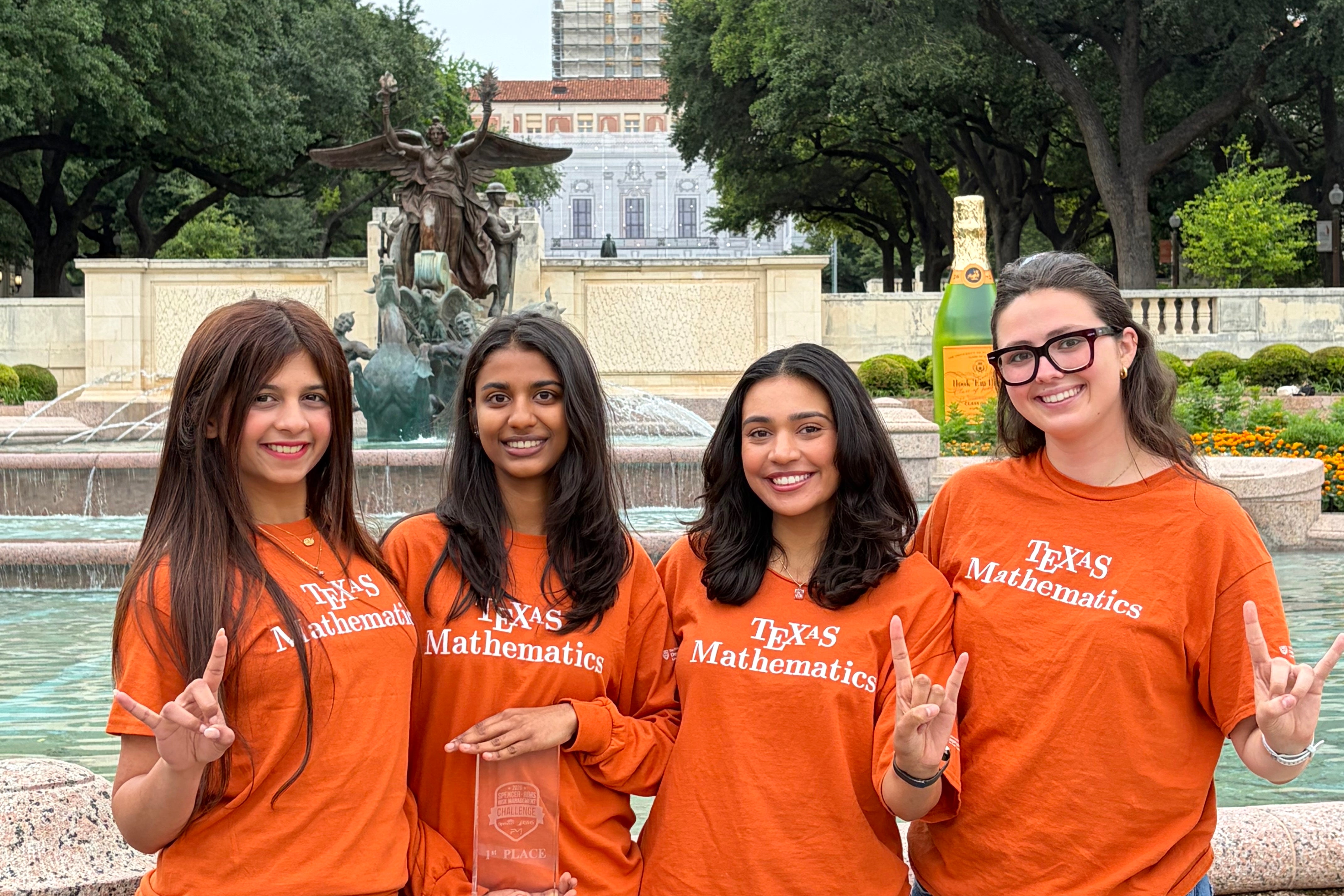 Four UT students holding a trophy near the Tower